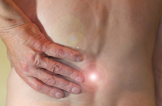 Eine Hand liegt auf einer schmerzenden Stelle am unteren Rücken
